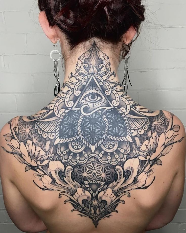 the back of a woman's neck with an intricate tattoo design on her chest