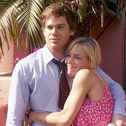 a man and woman hugging each other in front of a building with palm trees behind them