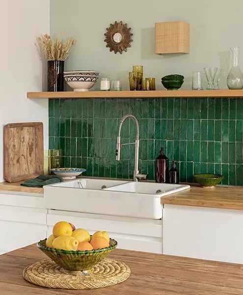 a bowl of fruit sitting on top of a wooden table next to a kitchen sink