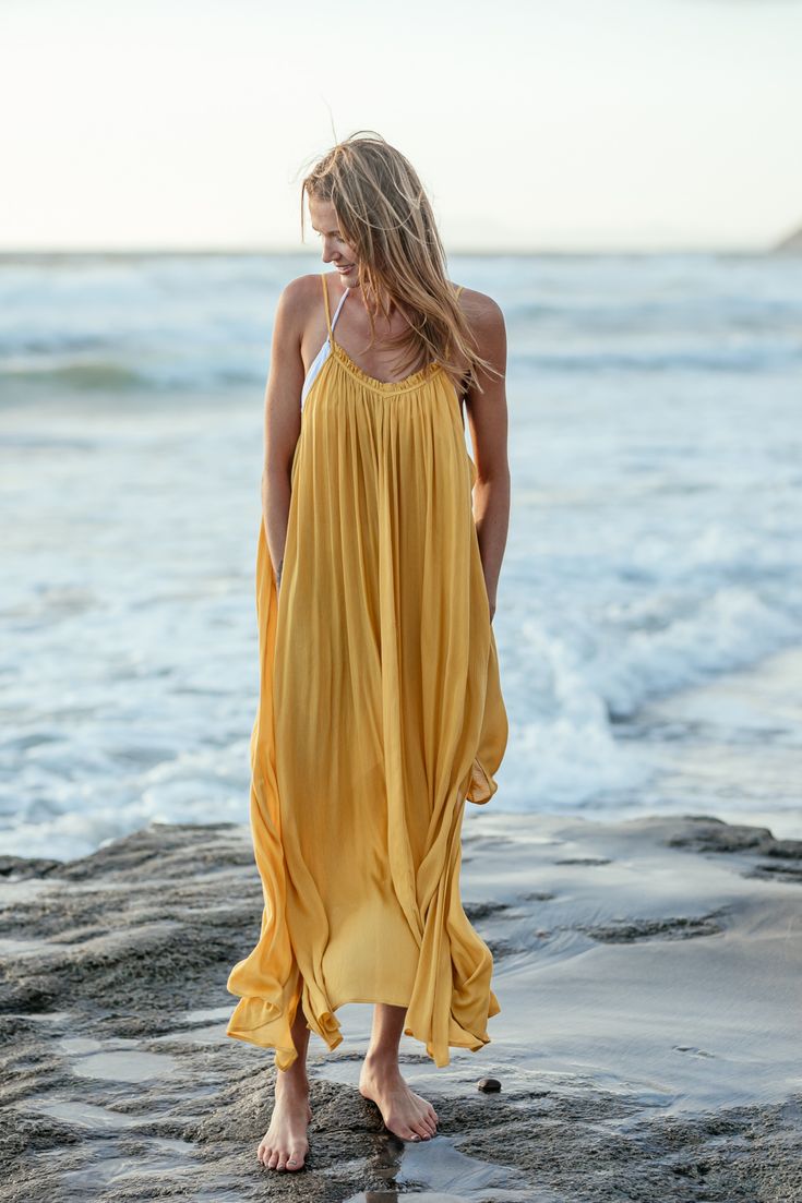 The Marigold Amalie Maxi Coverup is a dreamy beach dress for your next island-hopping adventure. The adorable ruffle neckline and deep V back have adjustable straps to accommodate your fit and make you feel a little sassy and confident. Complete with pockets large enough for your resort key and some lip gloss and in a gorgeous marigold color. Adjustable straps Machine washable Pockets! 100% rayon Our XS/S size is best for people 5'4 and under. Chic Gold Swimwear For Summer, Chic Gold Swimwear For The Beach, Gold Beachwear Swimwear For Spring, Chic Gold Beach Dress, Gold Summer Swimwear, Yellow Dress For Poolside Summer, Yellow Sleeveless Beach Cover-up Dress, Yellow Beachwear Dress For Poolside, Gold Swimwear For Beach In Spring