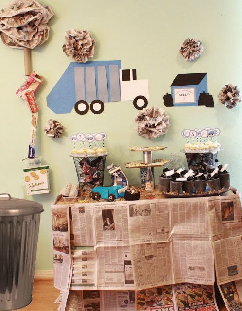 a table topped with newspaper and cupcakes next to a trash can filled with paper