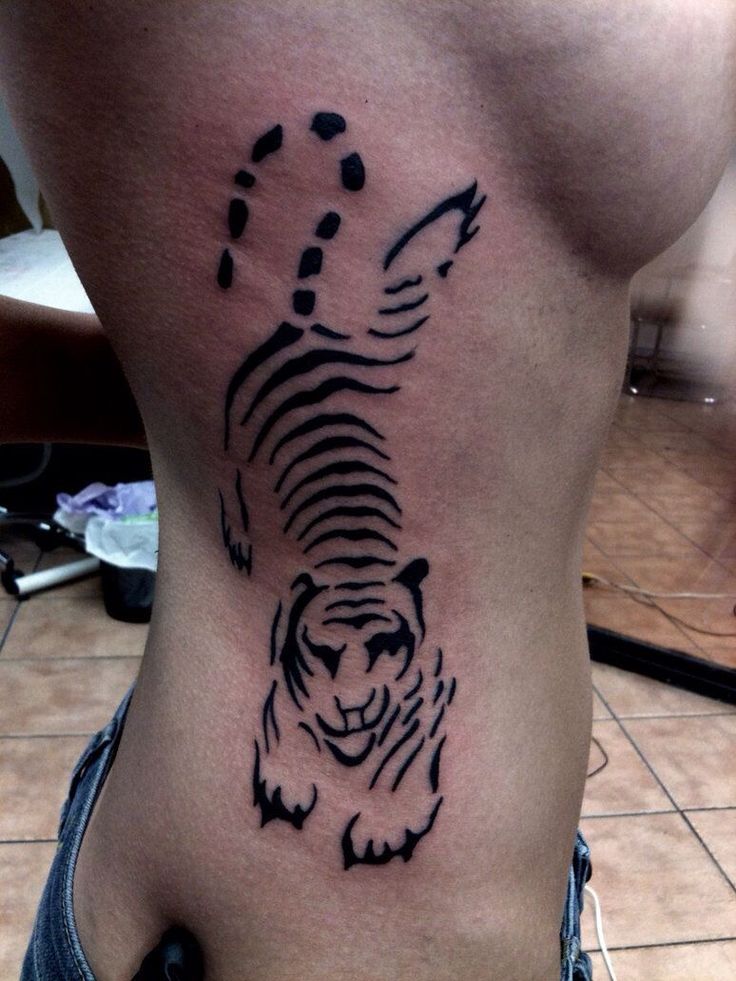 a black and white tiger tattoo on the side of a woman's stomach