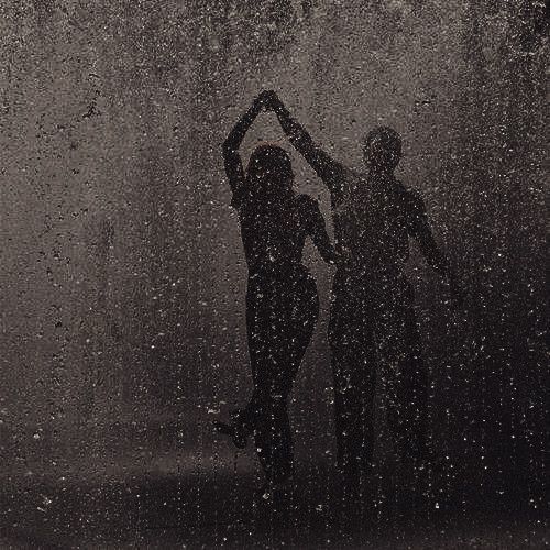 two people standing in the rain with their arms up and hands behind their heads,