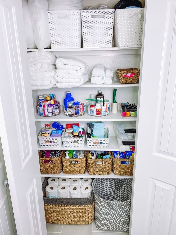 an organized pantry with baskets, toilet paper and other household care items on shelves next to the door