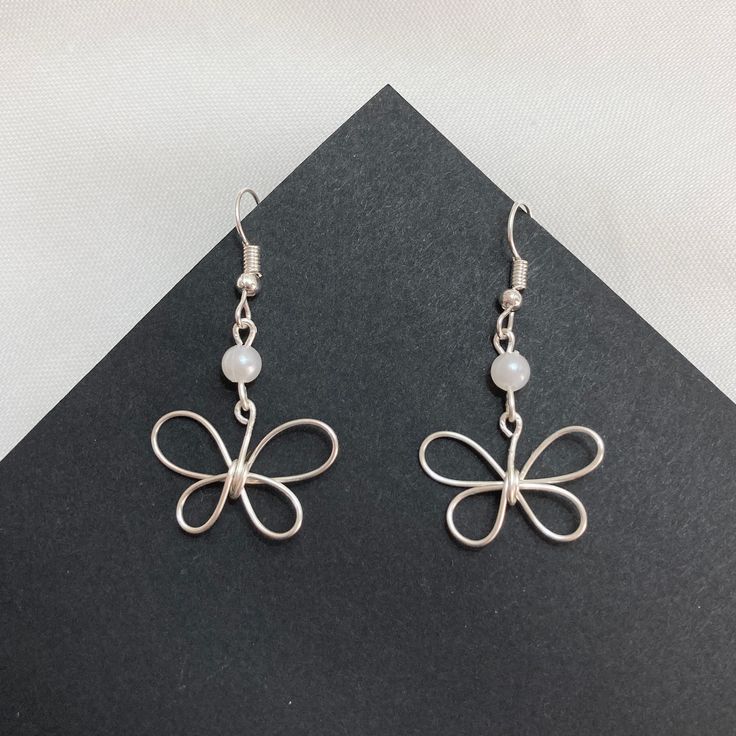 a pair of silver earrings sitting on top of a black surface