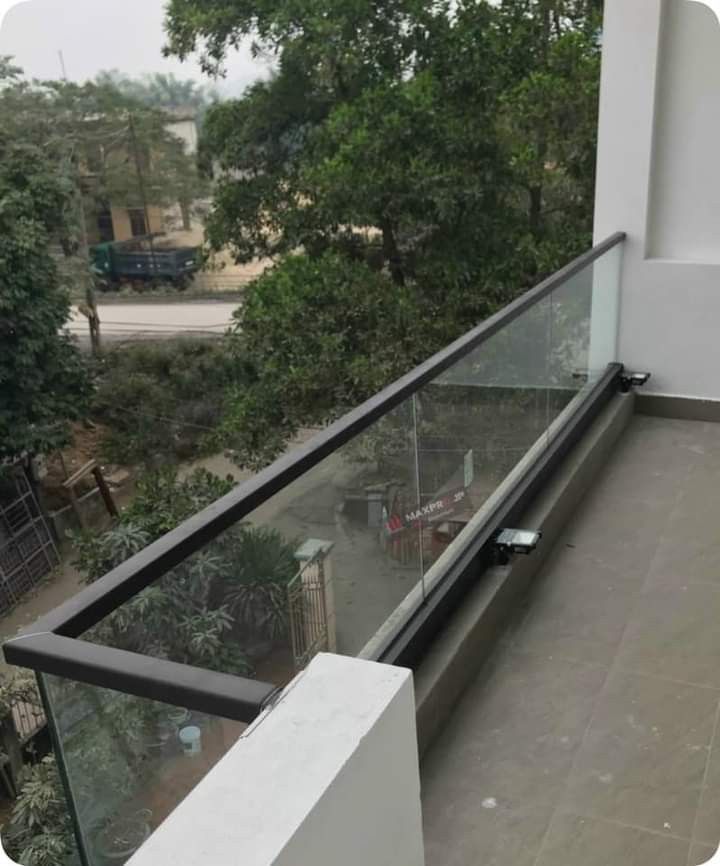 an empty balcony with glass railings and trees in the backgroung area