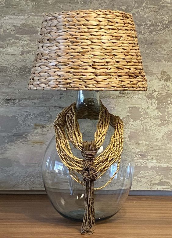 a lamp that is sitting on top of a wooden table next to a glass vase