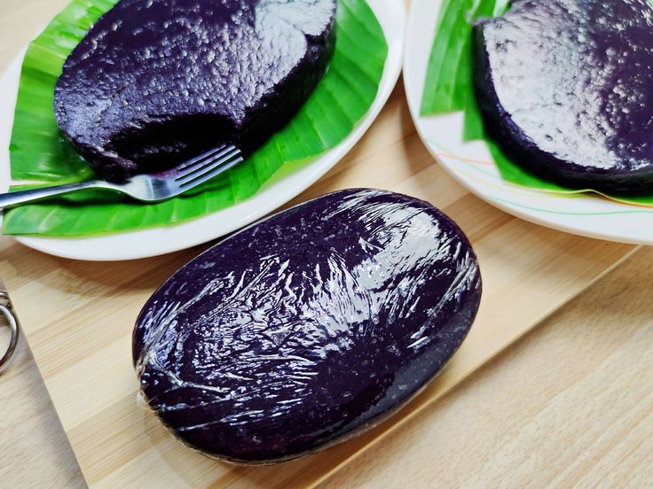 two plates with purple cake on them and a fork next to one that has been cut in half