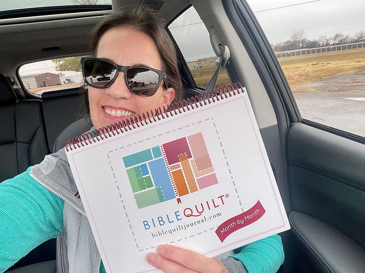 a woman sitting in the back seat of a car holding up a sign that says bible quilt