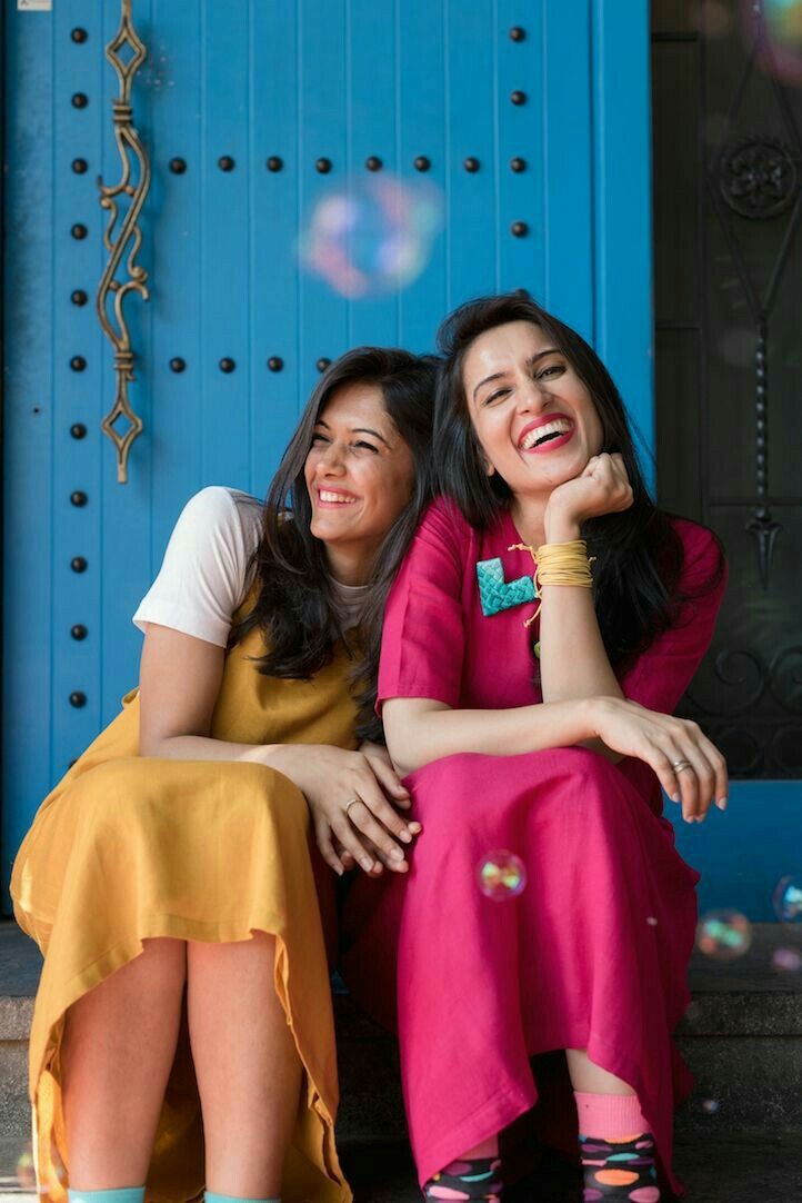 two women are sitting on the steps and one is wearing colorful socks while the other has her hand under her chin