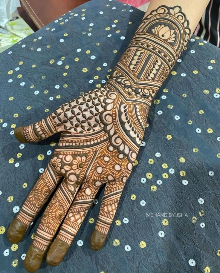 a henna on someone's hand that is sitting on a blue table cloth