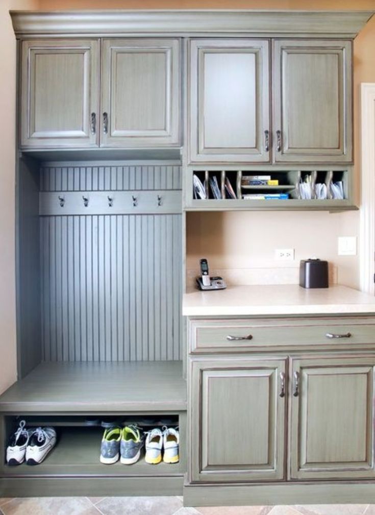 a kitchen with gray cabinets and shoes on the counter top, next to a coffee maker