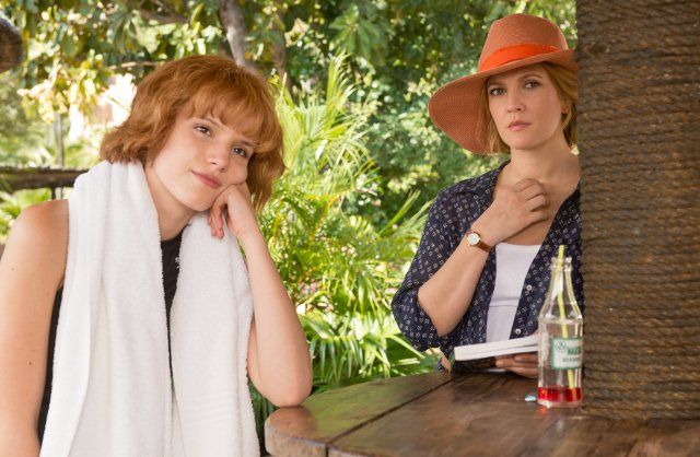 two women sitting at a table with drinks and towels around their necks, one woman has her hand on her chin