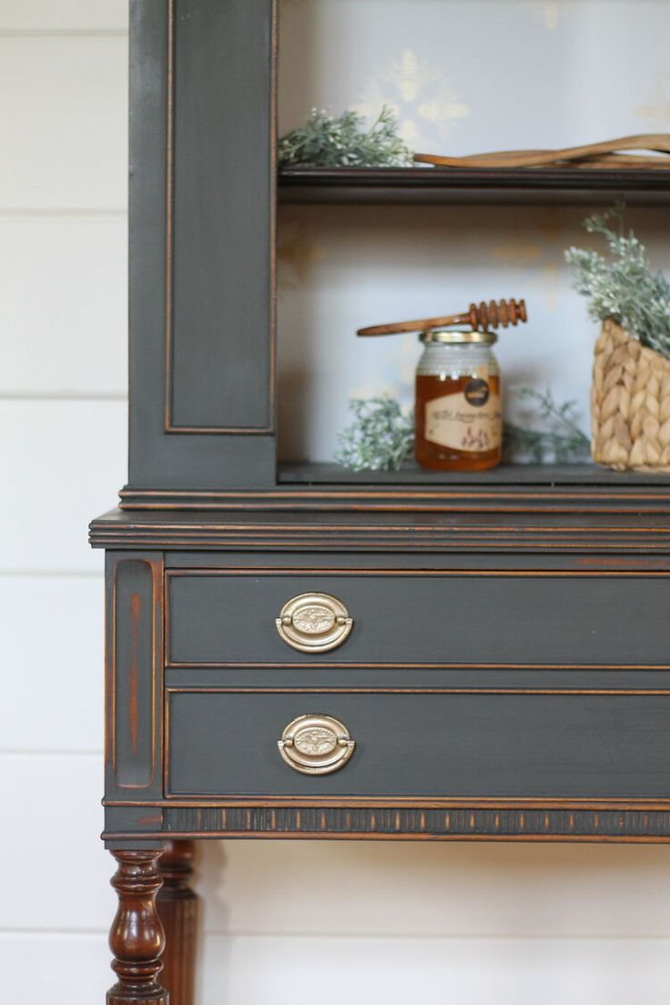 an old dresser is painted gray with gold trim