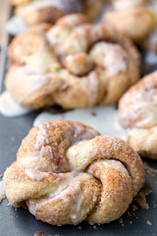 cinnamon rolls with icing sitting on top of a baking sheet next to other pastries