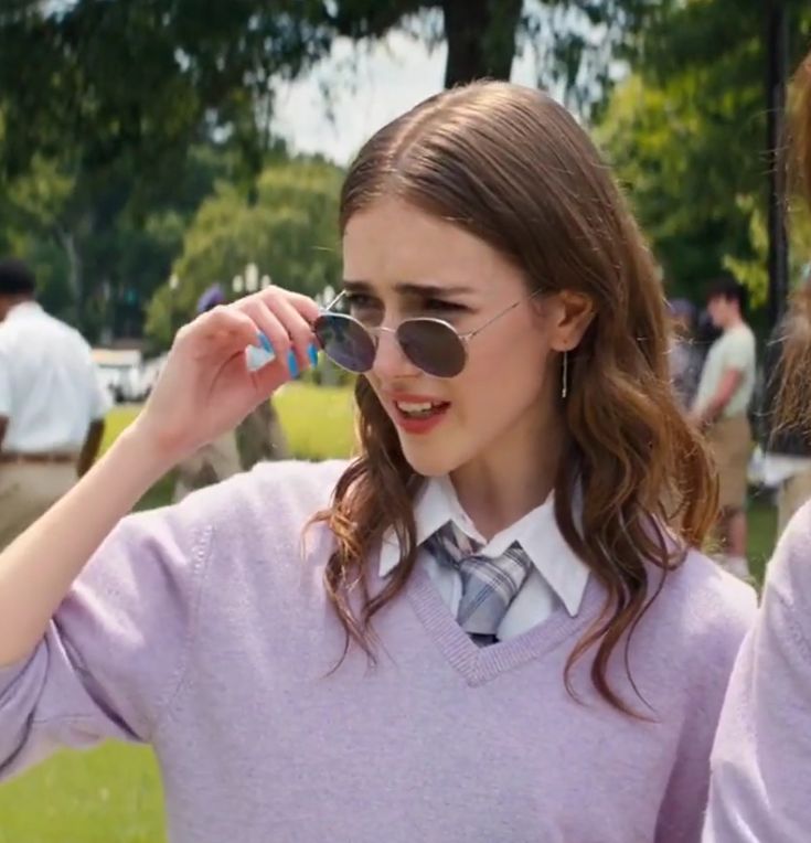 two girls in pink sweaters and ties are looking at something with round sunglasses on