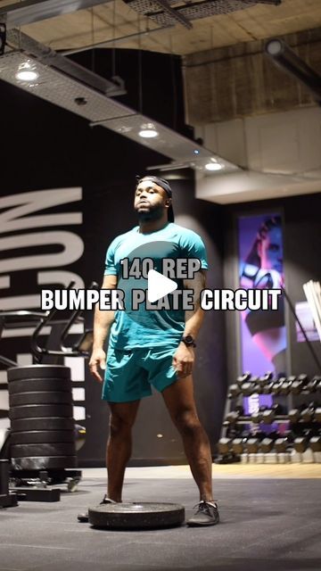 a man standing on top of a gym floor in front of a barbell machine