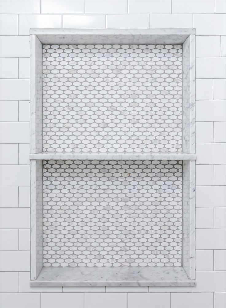 a white tiled wall with two shelves in it