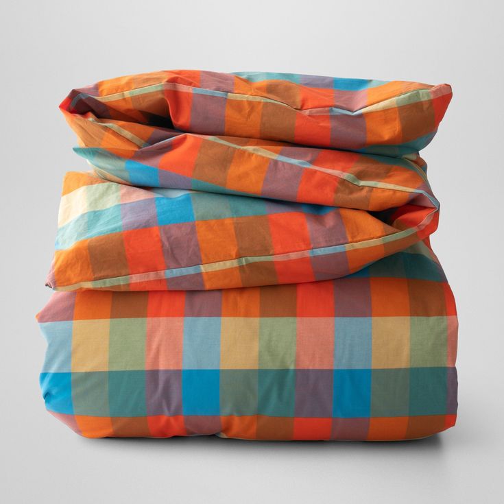 an orange and blue checkered comforter is folded on top of each other