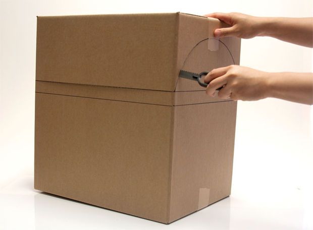 a person is opening a cardboard box with a pair of scissors in the bottom half