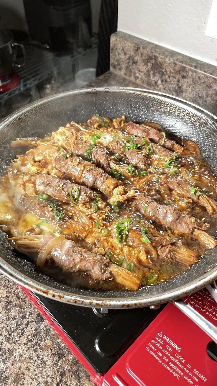 a pan filled with meat and vegetables on top of a stove