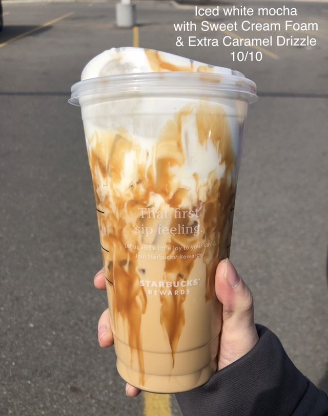 someone holding up a cup of ice cream and caramel drizzle on the street