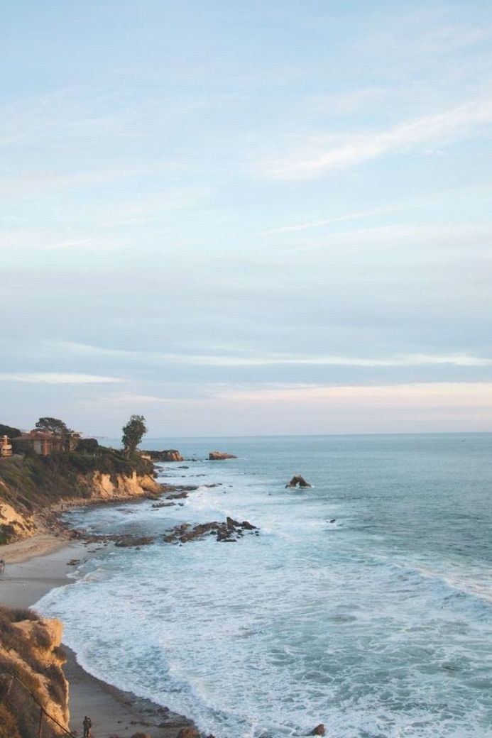 the beach is next to some cliffs and houses