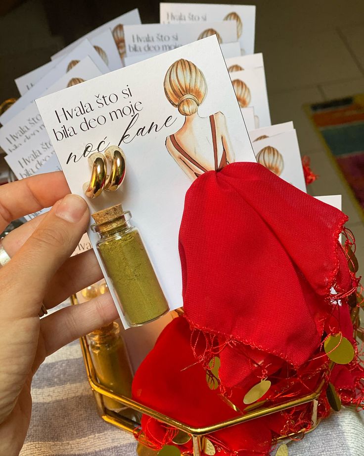 a person holding up a card next to a bottle of perfume in front of some cards