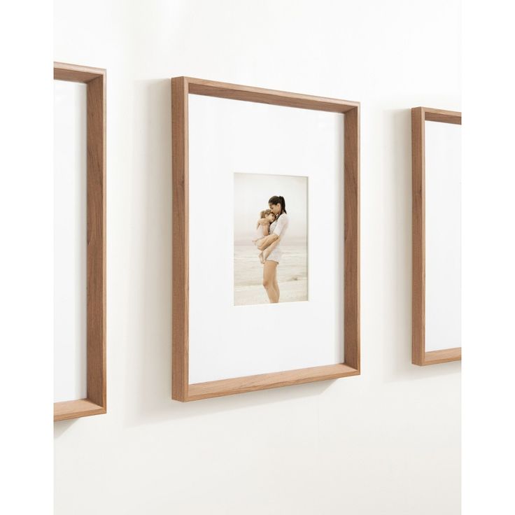 three framed photographs hang on the wall next to each other, one is holding a baby