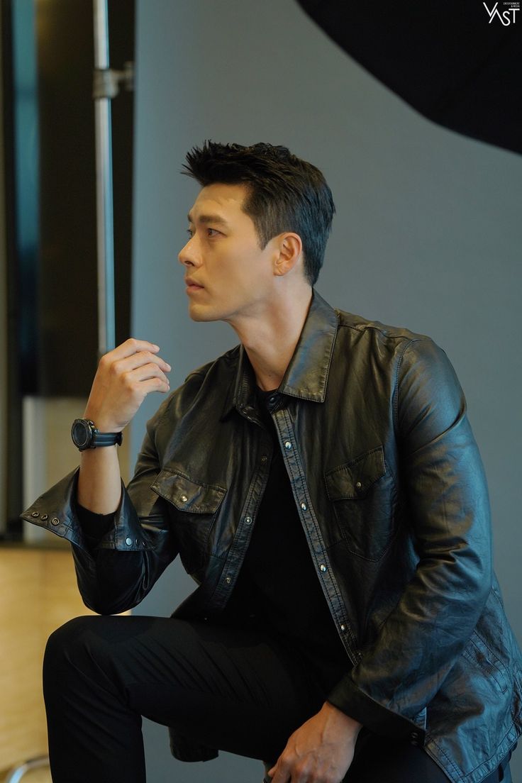 a man sitting on top of a chair wearing a leather jacket