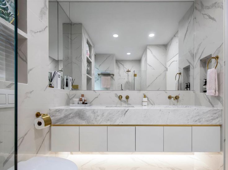 a bathroom with marble counter tops and gold fixtures