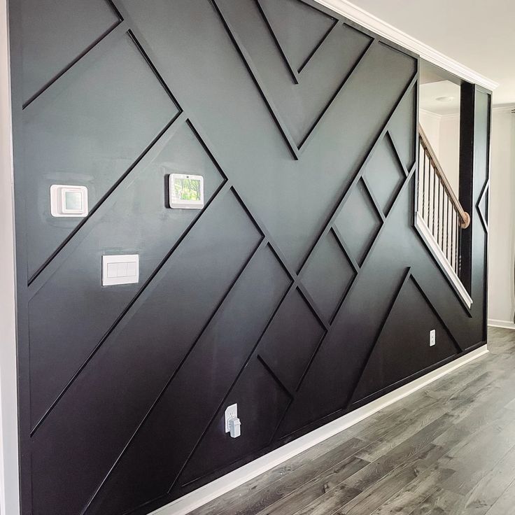 the wall is painted black and white with geometric designs on it, along with wooden flooring