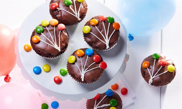 cupcakes with chocolate frosting and colorful candies are on a white plate