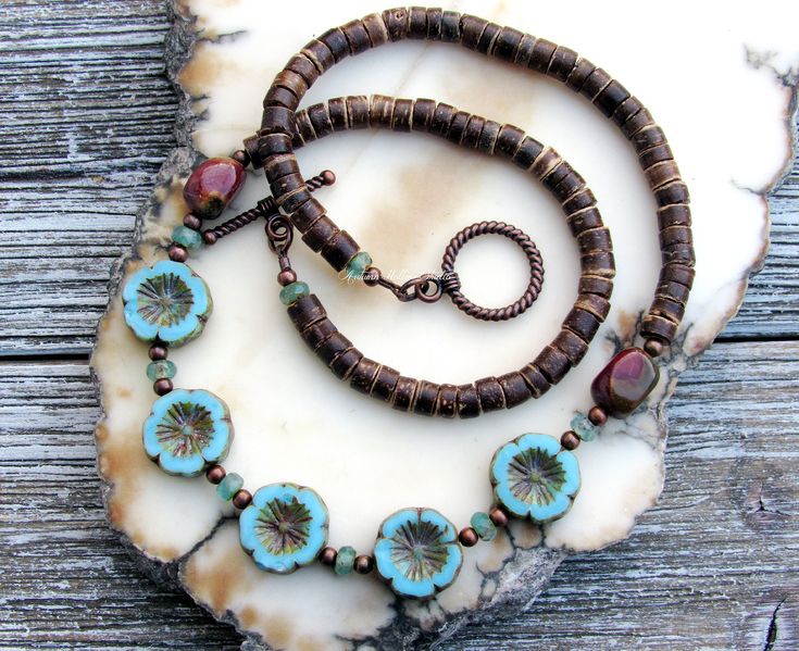 "Handmade \"Leilani\" Bohemian style beaded necklace. This necklace features 15mm aqua blue czech glass hibiscus flower beads, 3mm copper beads, 3x5mm picasso czech glass beads, 10x8mm red creek jasper gemstone beads, and 5mm natural coconut shell rondelle beads. Beads were strung on brown nylon coated thread cord.  \"Leilani\" in the Hawaiian language means \"heavenly garland of flowers\". The total necklace length is a little over 18 inches, and features an antiqued copper toggle closure. If a longer length is needed, I would be happy to add a small copper chain extension. Please message me first before placing your order to make arrangements for an extension. * All metals were made in the USA and are lead and nickel free. * Features czech glass and natural stone & nut beads. * Necklace Leilani Flower, Bohemian Jewelry Diy, Flower Beaded Necklace, Garland Of Flowers, Czech Beads Jewelry, Hawaiian Language, Czech Glass Necklace, Czech Glass Jewelry, Red Creek Jasper