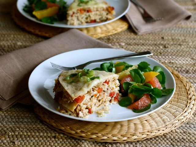 two white plates topped with food on top of a woven place mat next to a fork and knife