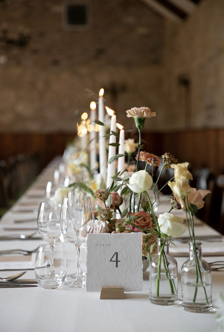 the table is set with candles, flowers and wine glasses for an elegant wedding reception