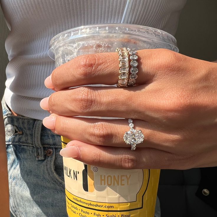 a woman holding onto a drink in her left hand and two rings on her right wrist