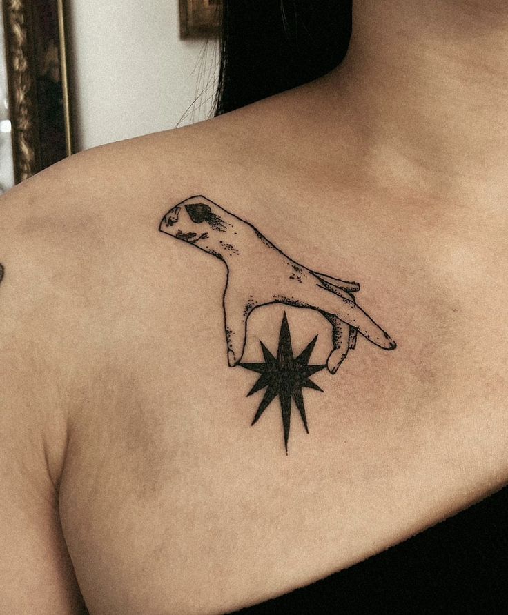 a woman with a tattoo on her chest has a star in the shape of a hand