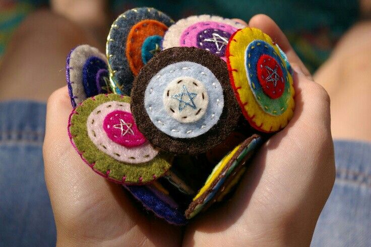 a person holding several small pieces of fabric in their hands with buttons attached to them