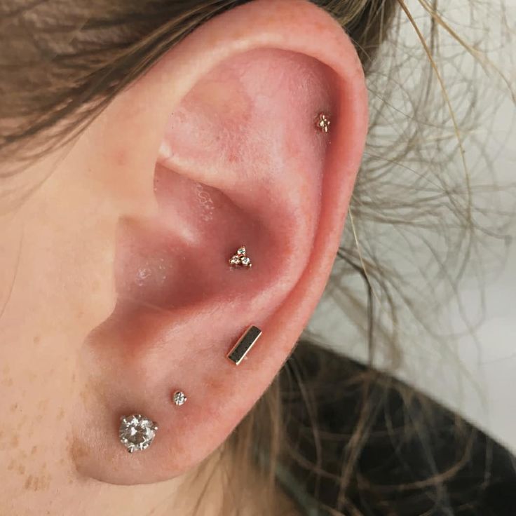 a close up of a person's ear with three piercings