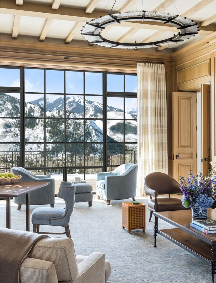 a living room filled with lots of furniture next to large windows covered in snow capped mountains