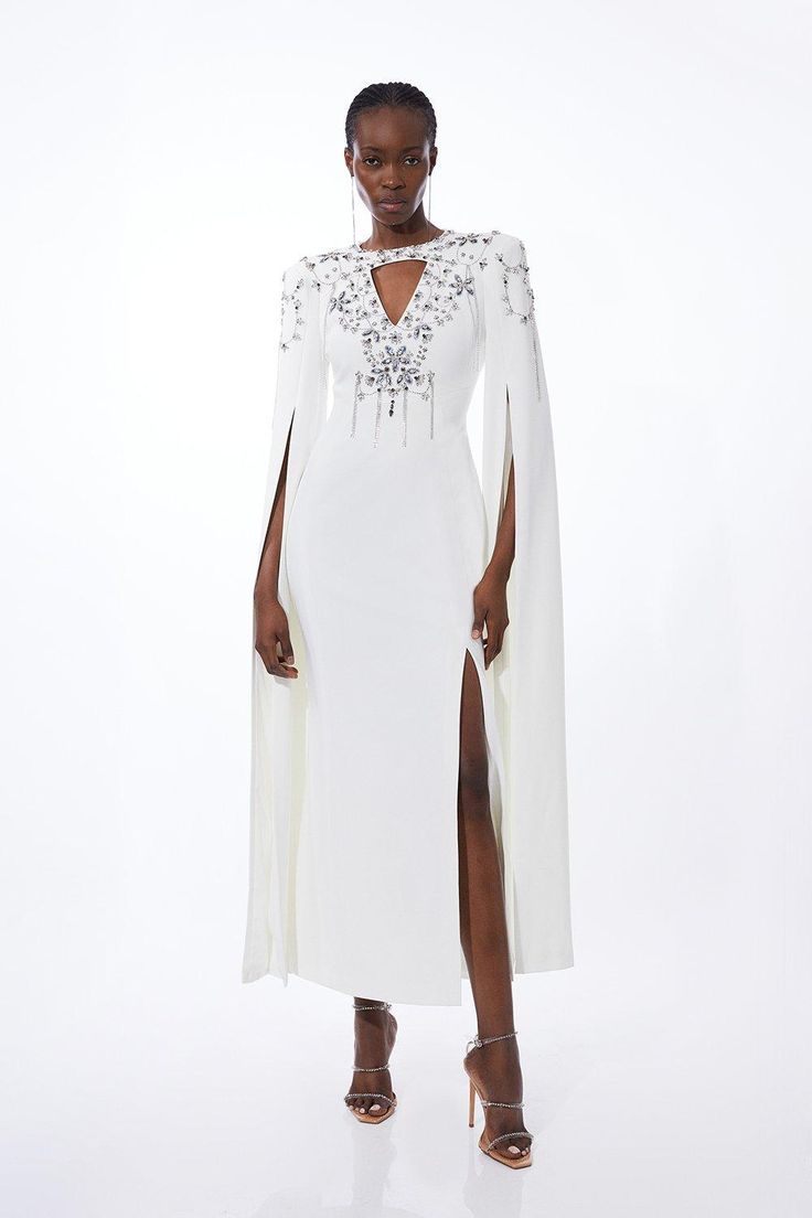 Draped In Luxury, This Dress Is Adored With Glistening Crystal Embellishments Along A Dramatic Cape Design, And Surrounding A Neck Cut Out Detail. A Midi Length Adds A Sophisticated Touch While A Split Hem Offers Allure. Pair With Barely-There Heels And Silver Accessories For Stand-Out Formal Wear.Crystal Embellishmentscut Out Detailcape Design Fitted Embellished Dress With Cape Sleeves, Evening Dresses With Pearl Embroidery And Cape Sleeves, White Embellished Dress With Cape Sleeves, Embellished Evening Dresses With Cape Sleeves, Hand Embellished Fitted Dress With Cape Sleeves, Fitted Hand Embellished Dresses With Cape Sleeves, Embellished Cocktail Dress With Cape Sleeves, Cocktail Dress With Embellished Cape Sleeves, Embellished Cocktail Dresses With Cape Sleeves