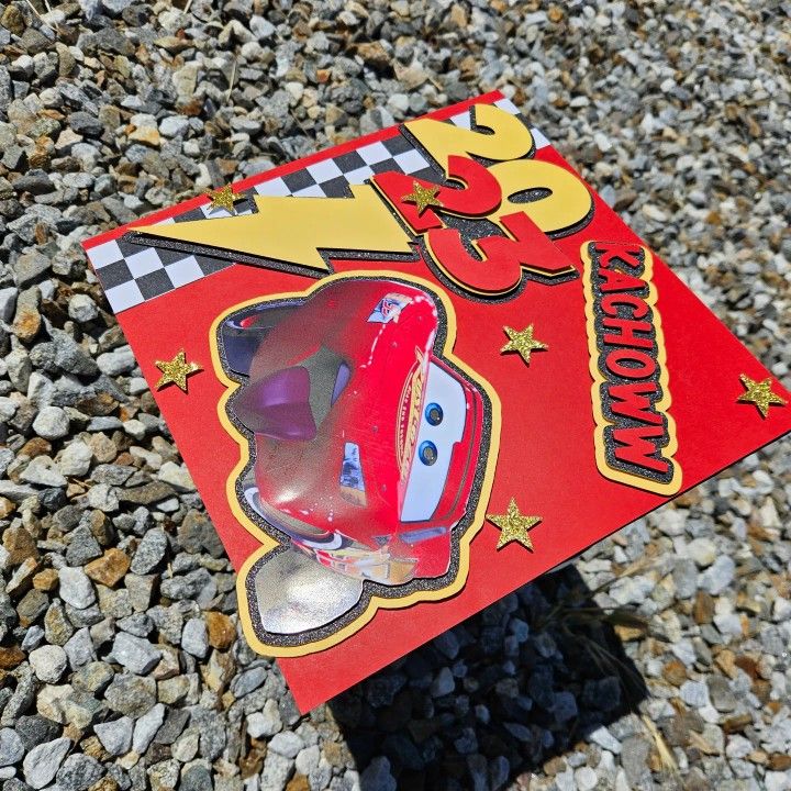 a red toy car sitting on top of a pile of rocks next to a sign