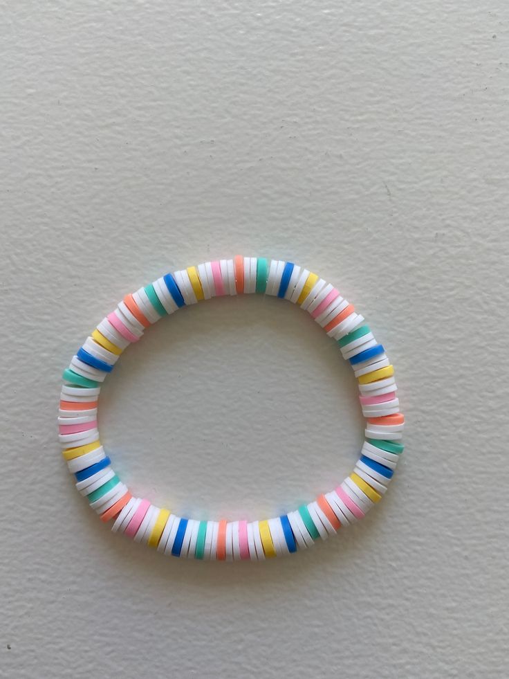 a bracelet made out of multicolored plastic beads on a white surface with a black bead in the middle