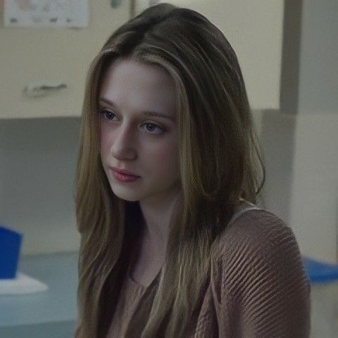 a woman with long hair sitting in front of a computer monitor looking at the camera