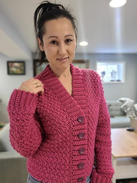 a woman wearing a pink knitted sweater with buttons on the front and back, standing in a living room