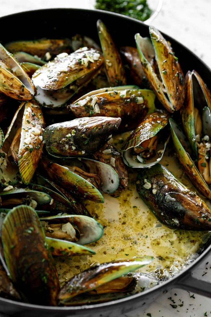 a pan filled with mussels and sauce on top of a table