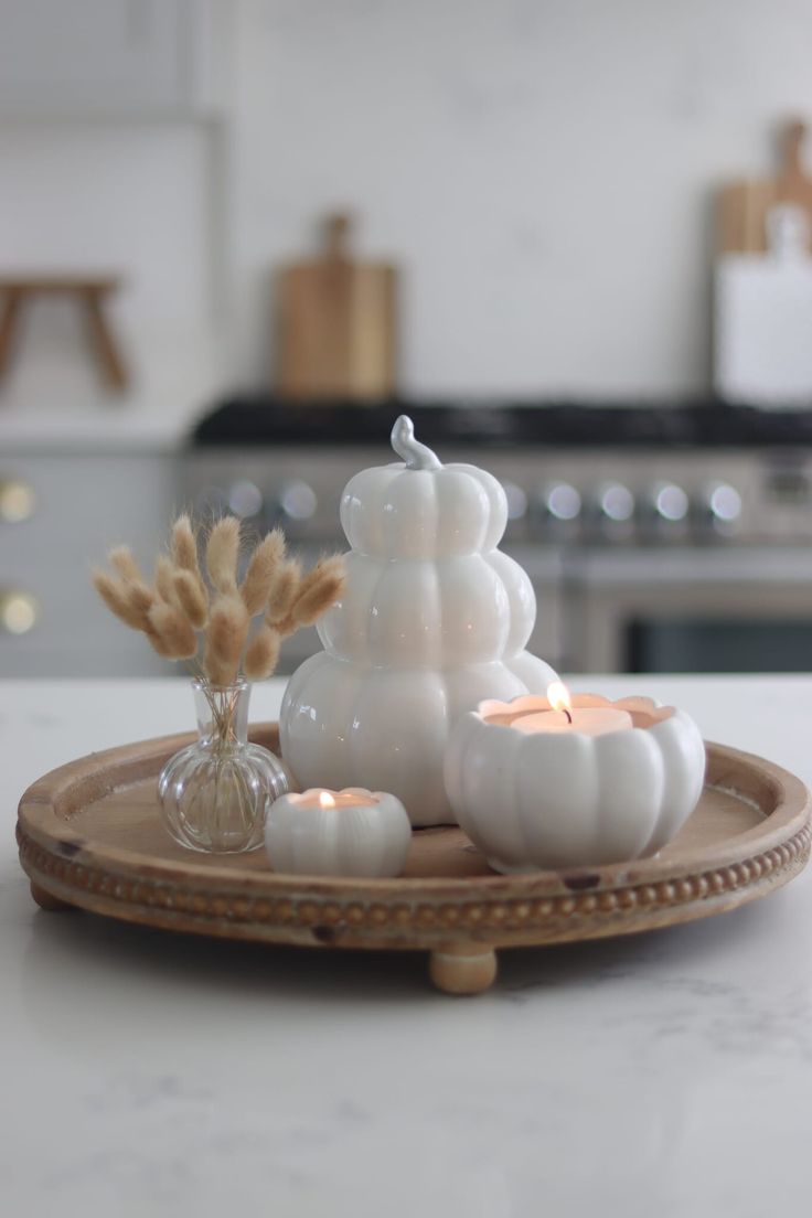 a plate with candles and some white pumpkins on top of it in a kitchen