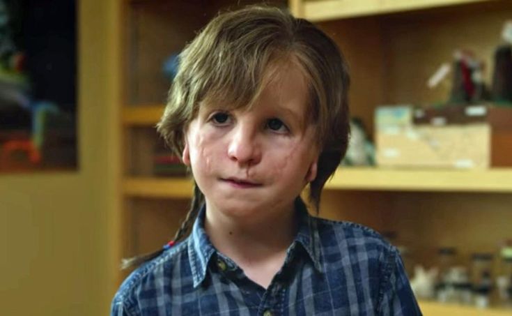 a young boy standing in front of a book shelf