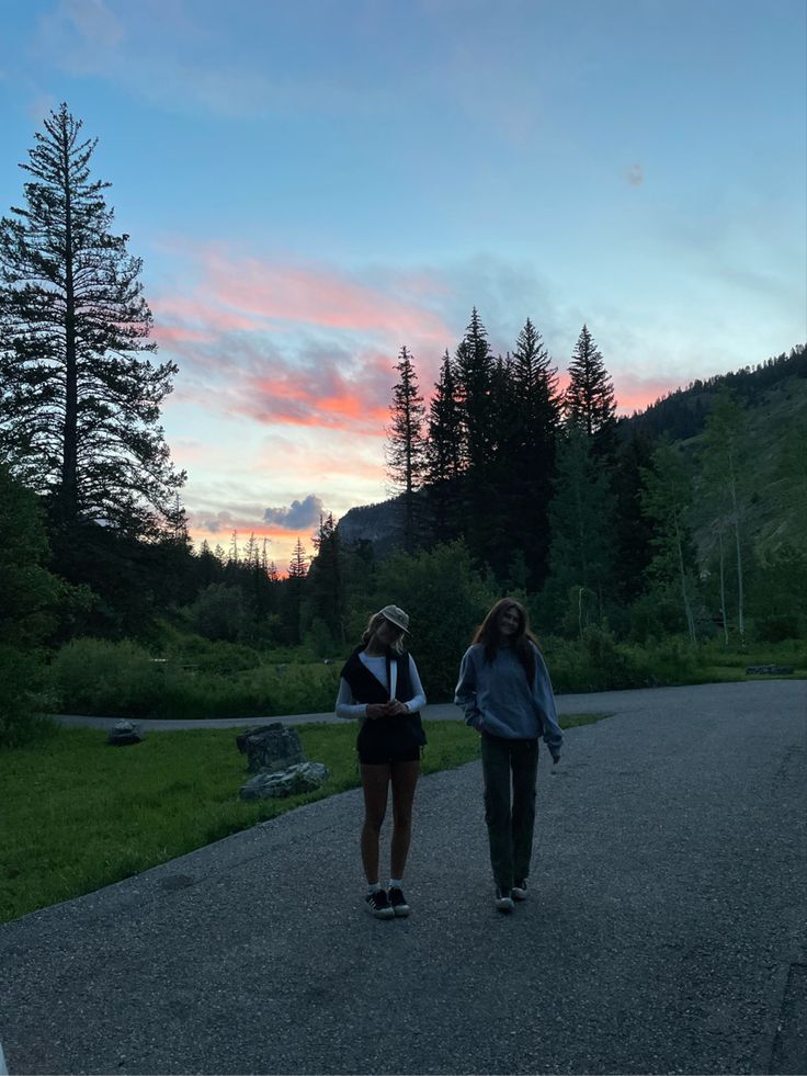 two girls walking down a road at sunset